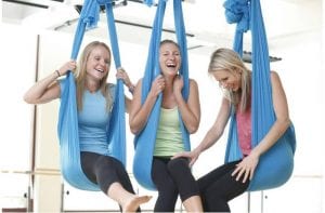 three aerial yogis smiling in aireal yoga hammocks